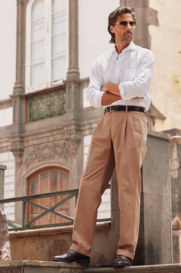 Model wearing beige HILTL CITY men’s trousers from the Spring/Summer 2026 collection styled in an urban city setting